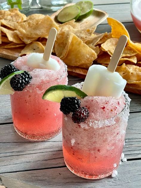 I am a huge fan of margaritas. My go-to favorite is a classic margarita on the rocks (and don’t skip on the salted rim), but during the Spring and Summer, I like to switch things up and go with this refreshing frozen version. Today I am sharing a Frozen Blackberry-Lime margarita recipe that is tart and sweet and salty all at once. And a fun bonus… it has a lime popsicle as a garnish. YUM!! This syrup is easy to make and stores for a week in the refrigerator. Outshine popsicles.… Popsicle Cocktail, Lime Margarita Recipe, Lime Popsicles, How To Freeze Blackberries, Margarita On The Rocks, Lime Margarita, Strawberry Daiquiri, Refreshing Food, Food Garnishes