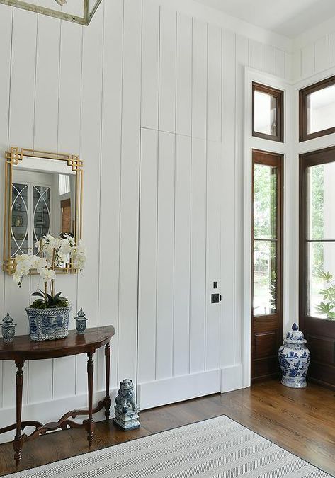 Cottage entry features a jib door with vertical shiplap trim and a gold leaf Greek key mirror over a demilune console table. Hidden Shiplap Door, Shiplap Hallway, Jib Doors, Jib Door, Dark Stained Wood Floors, Blue Chinoiserie Wallpaper, Shiplap Trim, In Home Library, Bath Goals