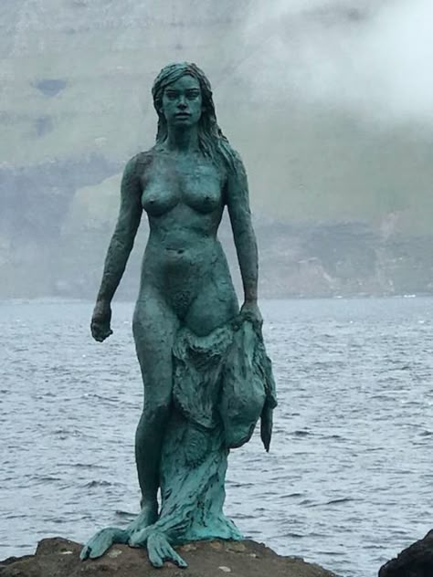 While on the island of Kalsoy, a visit to the village of Mikladalur (population 44) is a must - to see the selkie-statue - Kópakonan. The legend of Kópakonan is one of the best known folk-tales on the Faroe Islands. Selkie Statue, The Twelfth Night, Christian Festival, Woman Statue, Old Post Office, Water Spirit, Sculpture Projects, On The Rocks, Bronze Statue