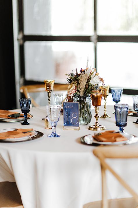 Wedding Reception Tablescape with Unique Blue Debutante Goblet Glassware and Dried Boho Centerpieces |Fall Wedding Design Inspiration Navy Blue And Copper Wedding Table Decor, Navy Terracotta Wedding Table, Navy Fall Wedding Decor, Terracotta And Blue Wedding Decor, Terracotta And Navy Centerpieces, Blue And Orange Wedding Table Settings, Navy Blue Fall Wedding Centerpieces, Terracotta And Blue Wedding Palette, Terracotta And Blue Bouquet