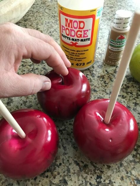 I love Fall decor, and this one is just so fun and looks good enough to eat! Take a look at how I made these, and perhaps you can make a few yourself. First, just pick up some fake apples from the craft store. Remove all the stems from your faux apples, and push the wood dowels into the tops. This how they will look... Now pour some corn cob on a paper plate- you can find this at a pet store! Next, lay a piece of wax paper onto your counter. Then pour some caramel co… Fake Food Christmas Ornaments, Diy Faux Candy Apples, How To Make Fake Candy Decorations Diy, Fake Bake Halloween, Caramel Apples Diy, Fake Candy Decorations Diy, Carnival Christmas, Fake Candy, Fake Food Props