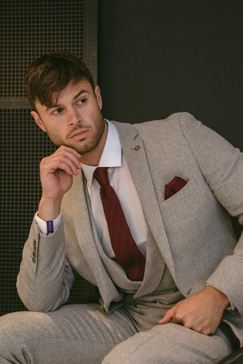 Male model sitting in a three piece light grey tweed suit withA burgundy tie and pocket square combined with a crisp white shirt. Clicks through to grey suits on Slater Menswear site. Light Grey Tweed Suit, Men's Grey Suits, Light Grey Suit Men, Summer Groomsmen, Charcoal Suits, Turtleneck Suit, Skye Costume, Light Grey Suit, Grey Tweed Suit