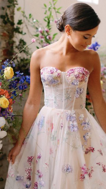 💐Floral Wedding Gowns💐  Which of these Hand-painted gowns is your favorite? A colorful wedding dress is the perfect focal point for a modern bride looking for some color for her wedding. Beautiful feminine shades of pink and purple! Wedding Dress With Colourful Flowers, Wedding Dress With Flowers On Skirt, Wedding Dress With Colorful Accents, Unique Wedding Dresses Floral, Reception Dress Floral, Floral Colorful Wedding Dress, Unique Colored Wedding Dresses The Bride, Pastel Floral Wedding Dress, Bright Floral Wedding Dress