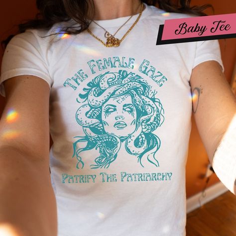 In stock. Going soon. The Female Gaze Baby Tee, Petrify the Patriarchy Shirt, Feminist Shirt , Activism, Women's Rights, Girls Power, Gift For Women Gift For Her only at �£16.00.. #TheFemaleGaze #GiftForHer #SpookyLiberal #PetrifyPatriarchy #GothFeminist #FemmeBabyTee #FeministTop #ActivismShirt #ShirtGift #ReproductiveRights Feminist Tops, The Female Gaze, Female Gaze, Girls Power, The Patriarchy, Feminist Shirt, Women's Rights, Womens Rights, Kids Tops