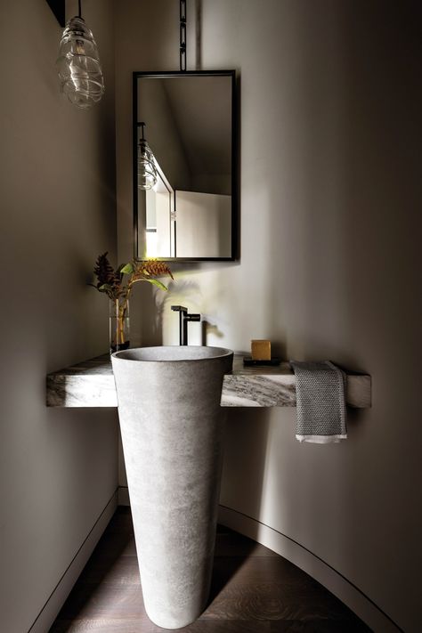 The powder room’s curved wall and “pinched corner,” as Knowles describes it, gives way to a custom suspended mirror and freestanding concrete sink tucked into marble from Ann Sacks. The sconce is by Tracy Glover Studio. Outdoor Powder Room, Suspended Mirror, Giant Kitchen, Corner Mirror, Curved Furniture, Concrete Sink, Corner Sink, Hall Interior, Marble Sinks