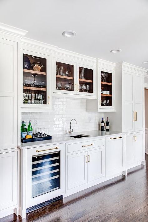 Glass cabinets over a square wet bar with sink featuring white linear subway tiles with a glossy finish. Pantry Bar Design, Wet Bar With Window, White Basement Bar, Wet Bar Ideas, Wet Bar Cabinets, Walnut Kitchen Island, Modern Bar Cabinet, Kitchen Wet Bar, Home Wet Bar