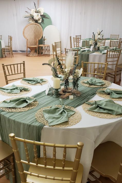 Embrace rustic charm at your event tables. White tablecloths and sage green table runners create a serene base with gold woven placemats and stylishly folded sage green napkins on top. The center hosts candles in themed holders, surrounded by rustic flower arrangements. A Chiara stand backdrop, draped in white and sage green spandex, showcases a boho-themed flower arrangement, completing the rustic allure for an enchanting celebration. 🌿✨ #RusticStyle #EventDecor Rustic Event Decor, Sage Green Napkins, Green Table Runners, Sage Green Table, Rustic Flower Arrangements, Event Tables, Flowers Candles, Green Napkins, Woven Placemats