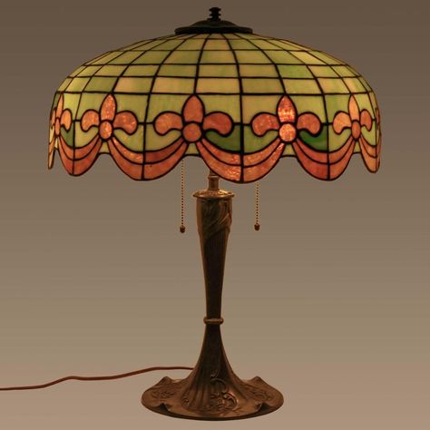 Antique American bronze and leaded glass table lamp by Wilkinson, circa 1910. The three light lamp having a dome shaped shade with striated leaded glass green & ivory tiles and having amber colored Fleur-de-Lis & swagged garland decoration to the base of the shade. The lamp is raised on the original bronze base decorated in an organic Art Nouveau design. The lamp is in very good condition and has been sympathetically rewired with period style materials, creates a warm pleasant light.  Bloomsbury Vintage Touch Lamp, Lampe Art Nouveau, 1920s Lamp, Fancy Lamp, Minecraft Torch, Art Nouveau Lamp, Eclectic Lamps, 70s Lamp, Tiffany Lamp Shade