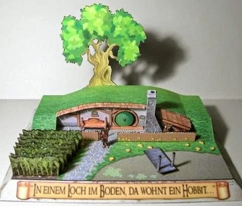 Hobbit hole diorama by Olli Bizer. Translated, the German phrase on the front of the model reads "In a hole in the ground there lived a Hobbit" which are the opening words to Tolkien's Th Hobbit Diorama, Casa Do Hobbit, Hobbit Party, Papercraft Download, Papel Craft, Hobbit Hole, Hobbit House, 3d Paper Crafts, Pop Up Book