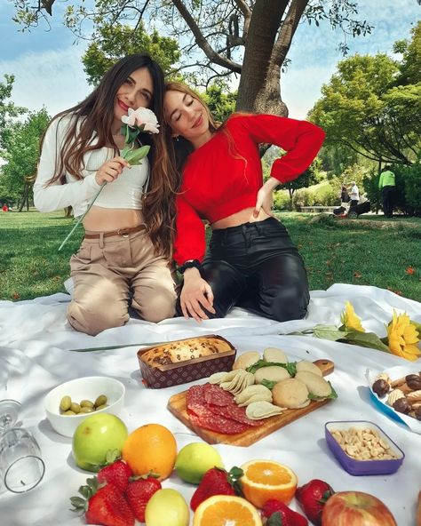 Dos mejores amigas sentadas en el suelo, en un parque haciendo un picnic, una de ellas está vestida con un top blanco a la cintura y otra con un top rojo manga larga a la cintura, detrás de ellas hay un árbol grande, y en frente hay frutas, como najaranjas, frutillas y manzanas, en una tabla hay cosas para picar,salame, pan, papas fritas, mani aceitunas Bff Picnic, Bff Ideas, Ideas De Poses, Ideas Picnic, Bff Photo, Photo Ideas