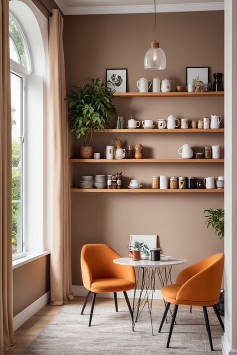 Cozy nook with orange chairs, a small table, and shelves displaying kitchenware against a brown wall. Coffee Corner With Chairs, Coffee Sitting Area In Kitchen, Modern Coffee Nook, Coffee Sitting Area, Sitting Area In Kitchen, Coffee Nook Ideas, Cozy Coffee Nook, Coffee Nooks, Cozy Window Nook