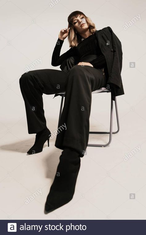 Download this stock image: Portrait beautiful woman with attitude sitting on a chair wearing black clothes posing on white background looking at the camera - 2BGECA9 from Alamy's library of millions of high resolution stock photos, illustrations and vectors. Sitting Down On Chair Poses, Woman Sitting On A Chair Pose Reference, Pose Reference Photo Sitting Chair, Poses On The Chair, Person Leaning Back In Chair Pose, Person Sitting In Chair Pose, High Fashion Chair Poses, Power Sitting Pose, Woman Sitting In Chair Pose