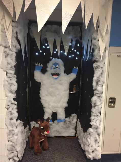 Christmas Door Abominable Snowman - battery powered snow flake lights behind black butcher paper dotted with glue & glitter and lots of snow fluff; Icicles made from poster board and glitter; Snowman made from white, blue, black and red paper covered with lots of snow fluff and a stuffed light up nose Rudolph. Best Classroom Christmas Door, Snow Fluff Decor, Rudolph Cubicle Decorations, Frosty The Snowman Decorations Office, White Christmas Classroom Decor, Rudolph Office Christmas Decorations, Kids Door Christmas Decorations, 3d Snowman Door Decoration, Blue Christmas Door Decoration