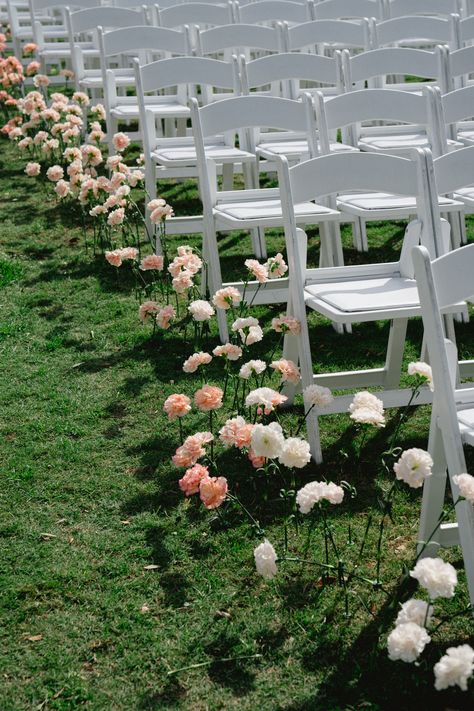 Pink and white florals lined up down the ceremony aisle with classic white chairs | ceremony details, ceremony inspo, ceremony florals, floral aisle Single Flower Aisle Wedding, Single Stem Aisle Flowers, Floral Ceremony Aisle, Flowers In Ground Wedding Aisle, Single Stem Aisle, Wedding Ceremony Set Up, Wild Flower Aisle, Flowers Ceremony Aisle, Floral Lined Aisle