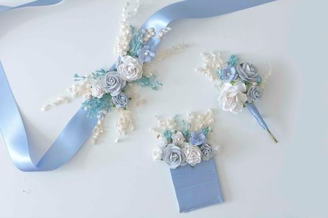 This beautiful corsage and boutonniere set decorated with flowers in serenity blue and white tones with dried and preserved flowers in white and light blue made completely by hand. Don't hesitate to contact me if you would like a special finish to match your wedding colors, I will be happy to do it for you. You can find a complete collection with these tones to organize your wedding color palette in the tones you were looking for, you can combine hair accessories along with accessories for the g Blue Corsage And Boutonniere, Spain Islands, Blue Corsage, White Corsage, Blue Boutonniere, Blue Flower Crown, Groom Buttonholes, Boutonnieres Prom, Corsage And Boutonniere Set