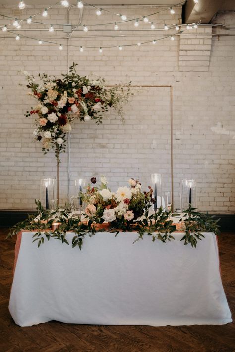 Sweetheart reception table with lush floral against white exposed brick wall | Image by Daring Wanderer Sweetheart Table Wedding With Bridal Bouquet, Married Couple Table Wedding Ideas, Sweetheart Table Bridal Bouquet, Sweetheart Table With Bridal Bouquet, Sweetheart Table Wedding Modern, Brick Wall Wedding Decor, Wedding Reception Wall Decor, Simple Sweetheart Table Wedding, Sweetheart Table Backdrop Ideas