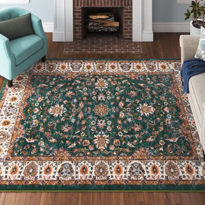 This area rug grounds your living room with a design inspired by traditional Oriental rug patterns. It's power-loomed from polyester, and it has a floral print in green, orange, and brown hues. Its material has excellent resistance to mildew and aging. We love how the 0.5" pile height makes it an ideal pick for adding a plush stage setter to your living room or bedroom. Best of all, this rug is stain-resistant, so it's ready to handle regular use. We recommend pairing it with a rug pad to preven Bold Living Room Rug, Jewel Tone Rugs Living Rooms, Cottage Core Living Room Rugs, Terracotta Rug Bedroom, Green And Blue Rugs, Emerald Green Rugs, Green Rug Bedroom Aesthetic, Plush Area Rugs In Living Room, Orange And Green Home Decor