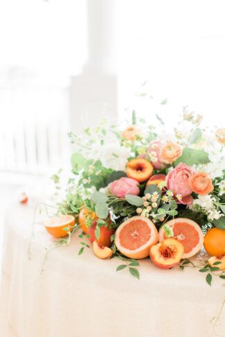 Playful Peach + Citrus Summer Wedding reception table flower centerpiece idea using a mix of fruits and floral arranagements in orange, coral and peach with hints of fresh vibrant greenery.   https://www.confettidaydreams.com/playful-peach-citrus-summer-wedding-ideas/  #peachwedding #coralwedding #summerwedding #citruswedding #whimsicalwedding #romanticwedding Grapefruit Wedding Decor, Citrus Floral Arrangement, Spring Centerpiece Ideas, Italian Event, Summer Wedding Ideas, Summer Wedding Reception, Fruit Wedding, Citrus Wedding, Fruits And Flowers