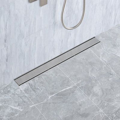 The linear format of this stainless steel tile insert linear grid shower drain offers a decorative solution to standard shower plumbing fixtures. With a sleek, sophisticated profile that maximizes both form and function, the long rectangular drain format removes water from the shower pan with ease. A removable strainer basket prevents pipes from clogging while the versatile drain configuration can be installed with a square grid pattern panel or without. The industrial-inspired design provides a Shower Drains Linear, Shower Bench Under Shower Head, Tile Shower Drain, Shower Plumbing Fixtures, Linear Drain Shower, Square Grid Pattern, Primary Bed, Shower Plumbing, Stainless Steel Tile