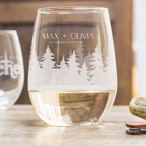 "PERSONALIZED WOODS STEMLESS WINE GLASSES These personalized and etched stemless wine glasses come with a beautiful design featuring an array of forrest trees that wrap around the glass. The design is personalized with names and a date. These are perfect for a forest-themed wedding! They can be gifts for the wedding party, wedding favors, toasting glasses, or a beautiful way to display specialty cocktails! Each order comes with 1 glass. 🤩 CUSTOM DESIGN 🤩 Want to add anything extra, change the Mountain Destination Wedding Favors, Wedding Etched Glass Ideas, Woodland Fairy Wedding, Mountain Themed Wedding, Outdoor Wedding Favors, Specialty Cocktails, Etched Wine Glasses, Toasting Glasses, Wedding Glasses