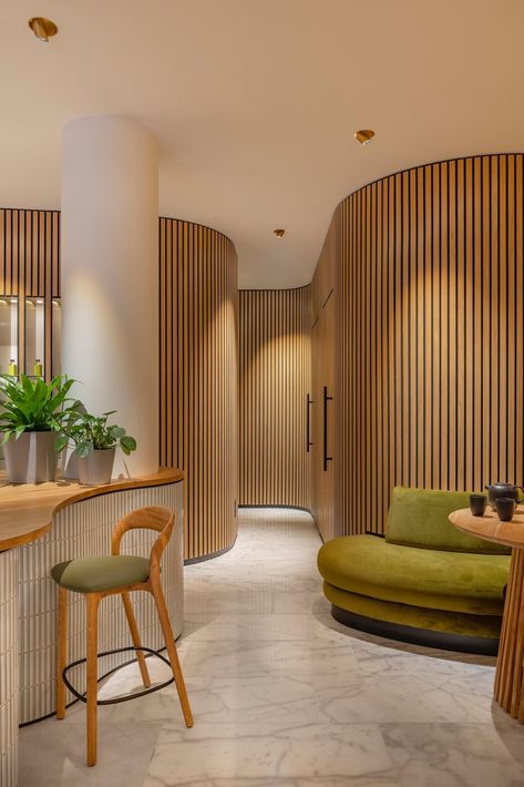 Blending into the organically shaped walls are the doors to the massage rooms, only noticeable by the black hardware. Wood Slate Accent Wall, Curved Walls Interior, Tambour Wall, Rock Pigeon, Cannes 2024, Concealed Door, Organic Interior, Spa Interior Design, Concrete Interiors