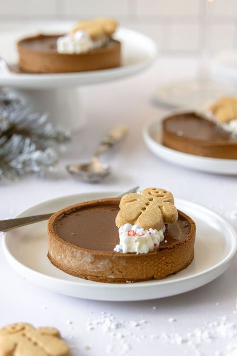 This gingerbread chocolate tart is a beautiful dessert for your Christmas day table that will wow your guests and it's easy to make too. A spiced chocolate ganache filling sits inside a beautiful crisp gingerbread pastry case, decorated on top with whipped cream, gingerbread men and festive sprinkles. #gingerbreadtart #gingerbreadchocolatetart #gingerbread #pastry #christmasdessert #chocolateganache #gingerbreadpastry #festivebaking Christmas Tart Recipes Mini, Gingerbread Tart Recipe, Cozy Christmas Desserts, Christmas Patisserie Ideas, Christmas Chocolate Tart, Chocolate Gingerbread Tart, Christmas Plated Desserts, Gingerbread Chocolate Tart, Christmas Day Desserts Ideas