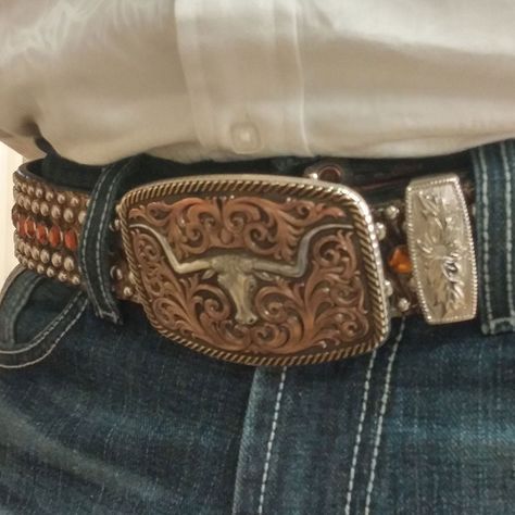 Antiqued Tri-Color Champion Texas Longhorn Belt Buckle - Made in the USA! Free Shipping! Please allow 7-14 days to ship A classically themed Western buckle has a light antiquing covering the silver and yellow gold finishes. A center Champion Texas Longhorn steer gold finished figure sits surrounded by thick flowing filigree. This steer figure differs from our regular steer figure with a notched horn design. A thick edge of rope finishes the buckle design. Standard 1.5 inch belt swivel. Made in the USA! Dimensions: Width: 3.75" Height: 2.625" Length: 0.789" Materials : 99.9% fine silver and 14 karat yellow gold plated over a brass base. Paint. Montana Armor protective finish to prevent tarnish. Warranty : Western and Trophy buckles have a lifetime limited warranty on manufacturing defects w Cowboy Belt Buckle Aesthetic, Country Belts For Women, Belt Buckle Aesthetic, Belt Buckles Cowgirl, Big Belt Buckle, Country Belt Buckles, Girls Belt Buckles, Western Belts For Women, Mlp Clothes