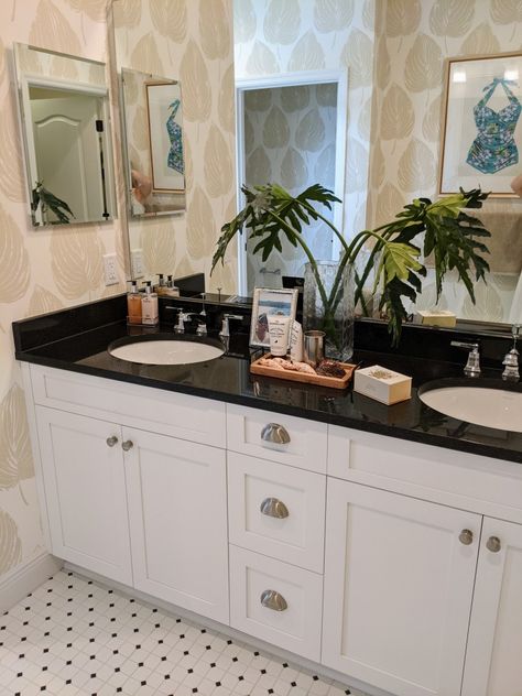 I love the use of wallpaper to bring this bathroom to life! White cabinets, black countertops, and a classic tile floor is seen often, however, the wallpaper makes it stand out. Imagine if they had just used paint on the walls. There would be no wow factor 😉 Bathroom Decor Dark Countertop, Bathroom With Black Marble Countertop, American Bathroom Aesthetic, Bathroom Decor Ideas Black Countertop, Bathroom Decor With Black Countertops, Black Countertop Bathroom Decor, Black Vanity Top Bathroom Ideas, White Cabinet Black Countertop Bathroom, Black Top Vanity Bathroom