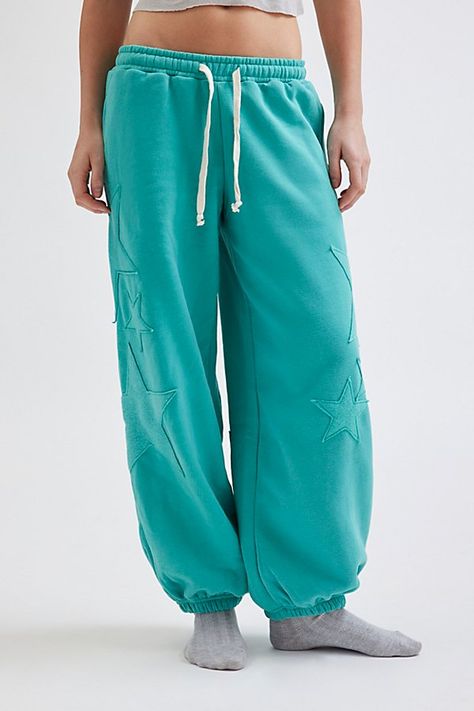 Ulta-cozy Out From Under sweatpant in a relaxed jogger style. Designed in a fleeced knit featuring a low-rise elasticated waist with drawstring detail, relaxed leg fit that cinches at the ankle and topped with star patches down the front & back of the legs. Only at Urban Outfitters. Features Out From Under Brenda star patch jogger sweatpant Slouchy lounge pant Super soft knit Low-rise elasticated waistline with drawstring tie Side pockets Star patches down the front & back of the legs Cinched el Teal Sweatpants Outfit, Sweatpants Design, Nike Winter Jackets, Comfy Ootd, Graphic Sweatpants, Star Patches, Cute Sweatpants, Clothing Wishlist, Drawstring Detail