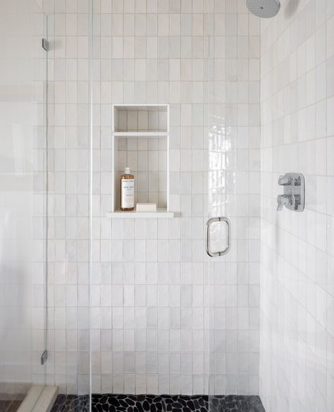 We selected a classic white zellige tile with a textured, natural look placed in a vertical design to give an unexpected look. The shower was grounded with black pebbles to keep it natural. We love the contrast between the two materials.⁠ ⁠ 📸 @mirandaestes Grey Vertical Subway Tile Bathroom, Textured White Bathroom Tiles, Vertical Shower Niche, Vertical Subway Tile Bathroom, White Zellige Tile, Subway Tile Showers, Subway Tiles Bathroom, Bath Tile, Shower Wall Tile