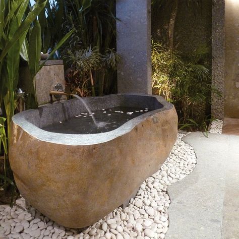 Huge river rock bathtub. Perfect to be placed outdoors, it is a natural bathtub that reminds of riverside stones with rounded edges. Sitting on a base made from small river stones, it is ideal for people who love being surrounded by nature. From the outside, it looks like a stone, but interiors with clean and sophisticated alcove tell the story of a modern bathtub. Made from rough beige granite, its outer surface nicely shows off intricate patterns of natural stone. Rock Bathtub, Concrete Bathtub, Bathroom Equipment, Bath Tube, Balinese Garden, Cottage Interior Design, Marble Bathtub, Cream Marble, Modern Lake House