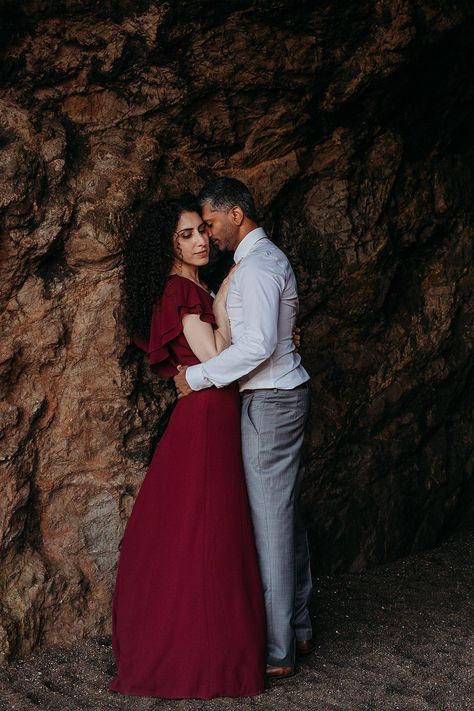 Lulu's long flowy burgundy dress.  Perfect for your engagement session.  Couples photoshoot in a little cave by the beach.  Beautiful warm tones and dramatic lighting.  Image of him loving on her. Engagement Photos Burgundy Dress, Burgundy Dress Engagement Pictures, Cave Outfit, Couple Cover, City Hall Wedding Photography, City Hall Wedding Photos, California Beach Wedding, San Francisco Engagement Photos, Couples Pics