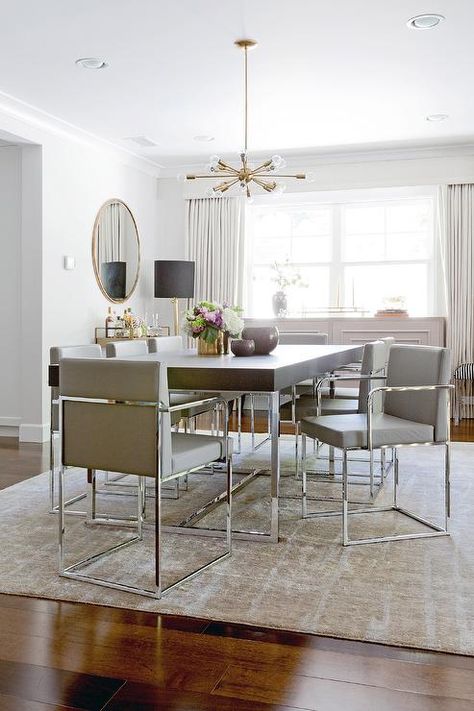 Contemporary dining room features a brass and glass sputnik chandelier illuminating a wood and chrome dining table lined with gray leather dining chairs atop a gold and gray rug. Chrome Dining Table, Grey Dining Room, Dining Room Contemporary, Leather Dining Room Chairs, Dinning Room Design, Gray Dining Chairs, Black Dining Chairs, July Decor, Ideas Hogar