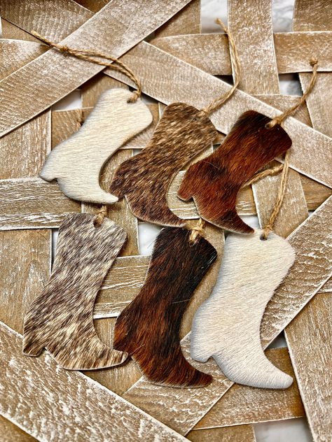 Cowboy boot christmas ornaments, set of 6,  for your western tree decor, Trending now country holiday themes , is a great gift for horse lovers, rustic farmhouse or those who love the wild west.  You get 6 cowhide ornaments,  cut from genuine Real cowhide measuring shape cowboy boot  3.0 / 3.0 mixed colors   Lassoed with   jute twines.  We have cows, cowboy boots, cow tags in sets , as well as keychains  multiples available message  Join us over in our Etsy store for more cowhide earrings, and genuine handmade leather earrings and jewelry , all our items are hand crafted here in the foothills of NC, a small family business  https://www.etsy.com/shop/riversistersleather/?load_webview=1&bid=FLlePKyUqo7Fpt4qVfnAq8tUDunt Christmas Western Decorations, Cowboy Boot Ornaments, Cowhide Crafts Diy Ideas, Western Christmas Tree Ideas, Cowhide Ornaments, Western Diy Decor, Cowhide Diy, Cowhide Crafts, Western Christmas Party