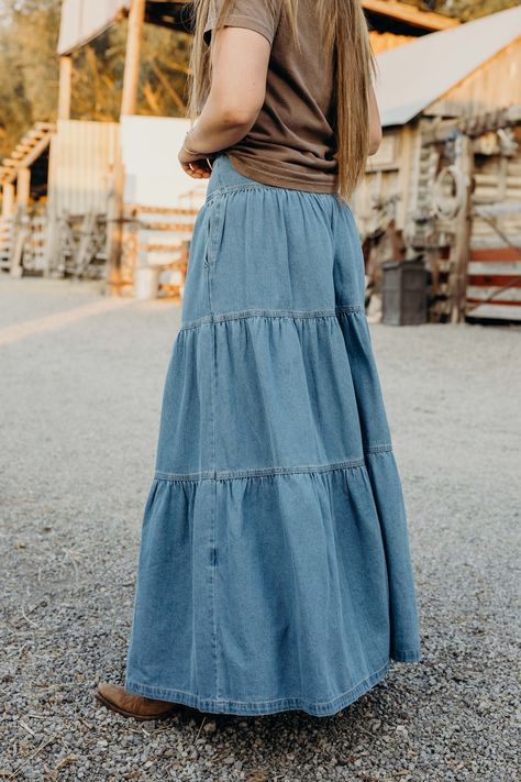 Get ready to twirl in style with The Lodonna Skirt. This light wash, tiered maxi skirt is made from soft denim and features side pockets for convenience. The elastic waistband provides a comfortable fit, while the western style adds a touch of flair. Haylee is wearing size small paired with the Horsin Around Tee and Parker Cardigan Tiered Denim Skirt Outfit, Tiered Denim Skirt, Jeans Into Skirt, Quilt Skirt, Diy Maxi Skirt, Long Tiered Skirt, Long Jean Skirt, Denim Skirt Outfits, Western Style Outfits