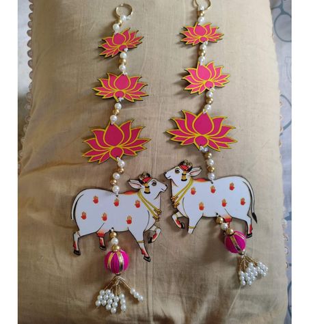 The cow is considered a sacred animal in Hinduism and holds great reverence in Indian culture. It is associated with various deities and symbolizes qualities such as abundance, fertility, and gentleness. The depiction of a cow in a wall hanging often adds an element of divinity and blessings to the space. The lotus, on the other hand, is a symbol of purity, beauty, and spiritual growth. It is highly regarded in Hinduism and Buddhism, often representing enlightenment and the unfolding of one's potential. Including a lotus in the wall hanging brings a sense of grace and serenity to the decor. The combination of the cow and lotus in a wall hanging can create a harmonious and auspicious ambiance, making it a popular choice for decorating homes, prayer rooms, and even during religious or celebr Pichwai Cow, Diwali Art, Diwali Ideas, Shubh Labh, Traditional Decoration, Lotus Bud, Entrance Wall, Paper Flower Garlands, Janmashtami Decoration