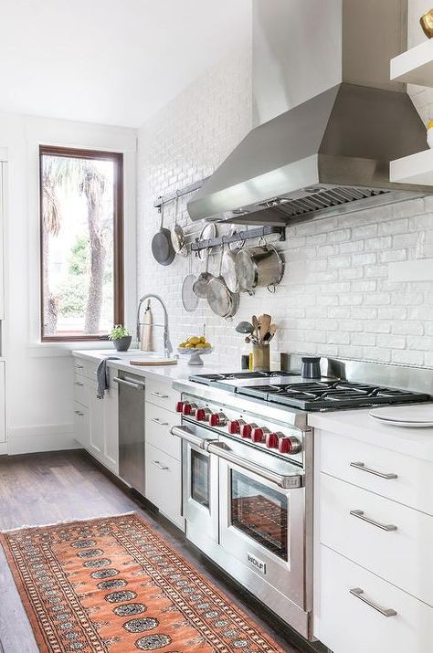 Who doesn't love upgrades? This gorgeous white kitchen features plenty starting with a Wolf dual range oven and stove, stainless steel vent hood and a dishwasher next to the white porcelain sink with a stainless steel pull out faucet. Painted Brick Backsplash, White Brick Backsplash, Exposed Brick Kitchen, Gorgeous White Kitchen, Brick Kitchen, Brick Backsplash, Farmhouse Kitchen Design, Kitchen Stove, Transitional Kitchen