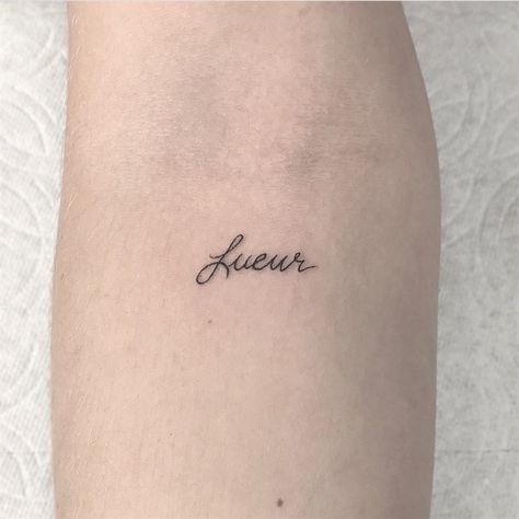 Word ‘Lueur’ which in French means ‘glow’ is inked in a minimalist font on the left inner arm French Word Tattoos, Small Words Tattoo, Glow Tattoo, Tiny Heart Tattoos, French Tattoo, Tatoo Inspiration, Meaningful Tattoo Quotes, Word Tattoo, Light Tattoo