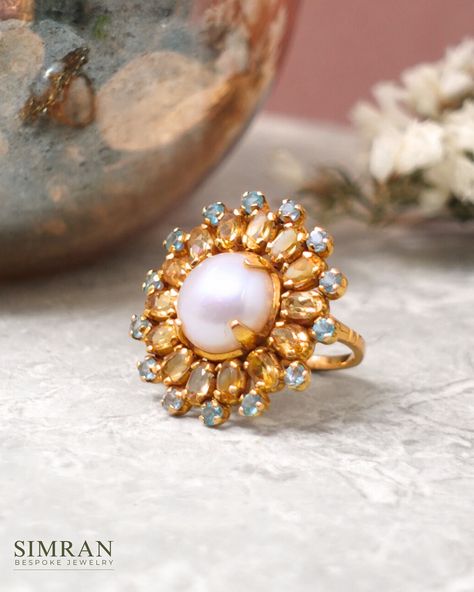 Presenting a one-of-a-kind cocktail ring that exudes summer elegance; a lustrous pearl centerpiece surrounded by a row of oval cushion-cut citrines, further encircled by vibrant blue topaz. This delightful combination of colors captures the essence of warm, sunny days. At Simran Bespoke Jewelry, each ring is a unique, bespoke design, crafted with meticulous attention to detail and rarely repeated. This commitment ensures that every piece retains its distinctive charm and freshness, making you... Pearl Centerpiece, Summer Elegance, Bespoke Jewellery, Vibrant Blue, Bespoke Design, Cocktail Ring, Cushion Cut, Cocktail Rings, Blue Topaz