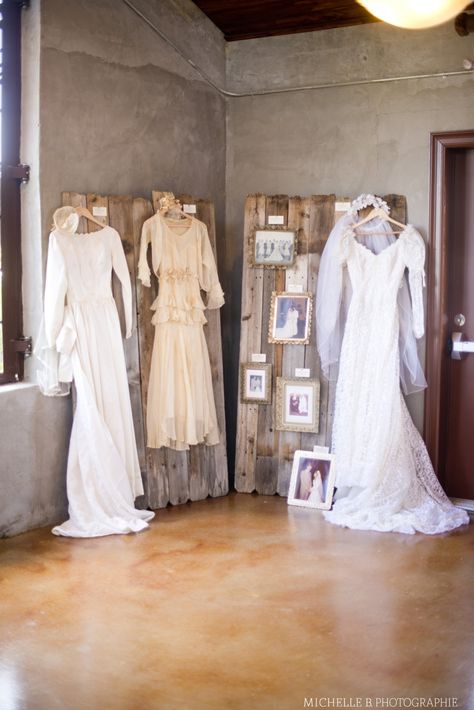 our wedding dress wall: featuring wedding dresses and pictures from our great grandmas, grandmas, and moms    DIY: fence posts, picture frames, picture cards Generation Wedding Dress Display, Wedding Dress Display At Reception, Mom Buttoning Wedding Dress Picture, Old Family Wedding Photo Display, Childhood Photos Wedding Display, Wedding Dress And Bridesmaid Dress Photo Hanging, Dress Display Ideas, Wedding Dress Display, Jordan Wedding