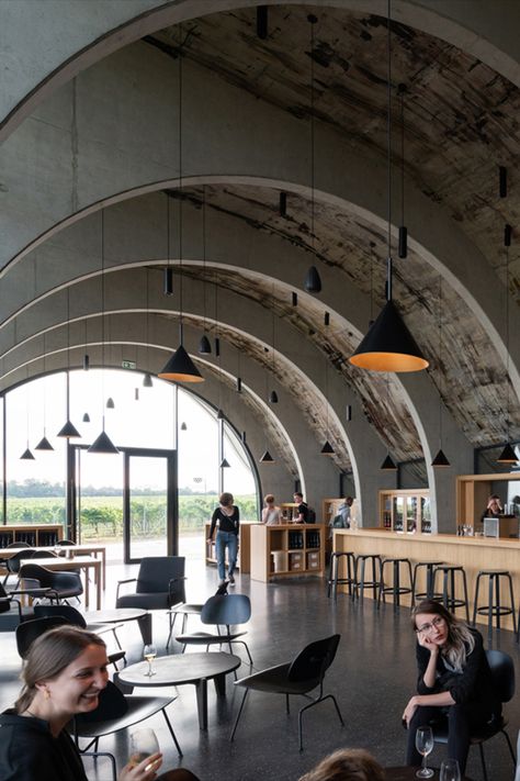 Sweeping curves soften the concrete and glass form of this Czech Republic winery, designed by local practice Chybik + Kristof. Lahofer winery in Dobšice features a visitor centre and tasting room, which takes cues from local Moravian wine-making traditions. It has a vast barrel-vaulted interior supported by a grid of arched beams, which emulate the style of the region’s wine cellars. #brutalist #brutalism #brutalistinteriors #interiors #concrete #restaurant #design Brutalist Restaurant, Winery Design Interior, Concrete Restaurant, Tasting Room Design, Winery Interior, Arched Beams, Industrial Style Restaurant, Urban Winery, Winery Design