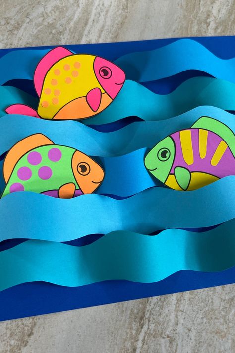 There’s nothing fishy about this craft. To create, download the template and print on your favorite color of Astrobrights paper, or use Astrobrights Bright White to color them yourself!. Cut around the outlines of fish and waves. Alternate the direction of the strips of paper to make the waves. Position your fish and glue. Create your own with our free template! *Difficulty: Easy* Moving Fish Craft, Diy Paper Fish Craft, Paper Waves Diy Crafts, Paper Fish Craft For Kids, Wave Craft, Fish Crafts For Kids, Paper Fish Craft, Paper Waves, Fish Paper Craft