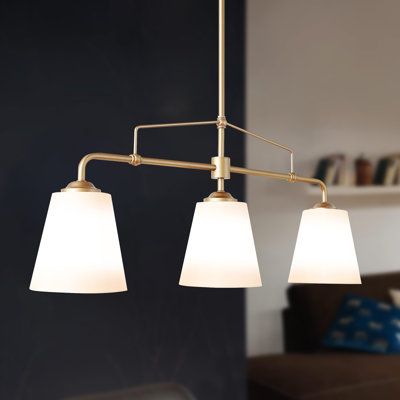 This Wistcross 3 - Light Shaded Linear Chandelier features a linear design that brings a modern and luxe aesthetic to your space. Made from metal with a gold finish for plenty of glam style, it includes a streamlined rod that connects to a horizontal bar and three separate holders. Each of these holders attaches to a white fabric empire shade that tempers the light from a single 60W bulb (sold separately). We love that the download is height-adjustable to better suit the size of your room, and it's also compatible with dimmer switches and sloped ceilings. Etta Avenue™ | Etta Avenue™ Lidia 3 - Light Shaded Linear Kitchen Island Chandelier white / yellowTextile / Metal | 14" H X 32" W X 6.5" D | Wayfair Light Over Island Kitchen, Lights Over Island, Linear Kitchen, Luxe Aesthetic, Chandelier White, Fabric Empire, Modern Lighting Chandeliers, Island Chandelier, Kitchen Island Chandelier