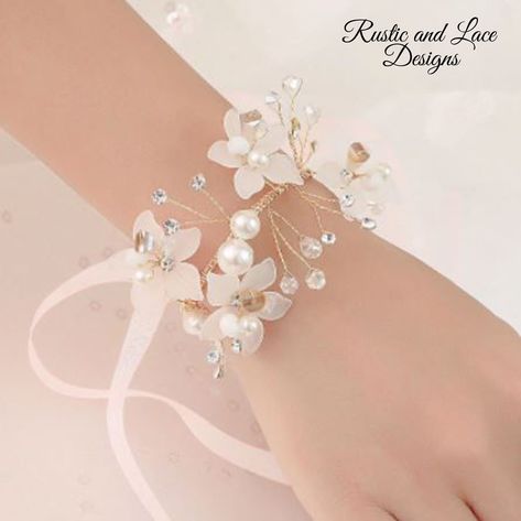 "Delicate wrist corsage bracelet with white flowers, clear crystals, pearls, sheer white ribbon, and gold flexible wire. This bracelet corsage is so dainty and pretty and even more so in person. It's perfect for a wedding or special occasion. *For more of my handmade corsages take a look here: https://www.etsy.com/shop/RusticandLaceDesigns?ref=simple-shop-header-name&listing_id=1177190086&section_id=37655117 All corsages are ready to ship today! - Measures approx. 2 1/2\" wide, 5 1/2\" long, and Bracelet Corsage, Wrist Corsage Bracelet, Hand Flower, Wrist Flowers, Wedding Hands, Style Royal, Prom Accessories, Hand Flowers, Flower Corsage