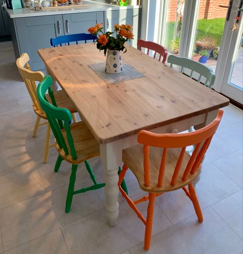 Colored Chairs With Wood Table, Colorful Painted Dining Chairs, Pop Of Color Kitchen Table, Different Color Chairs Dining Tables, Wooden Table With Different Chairs, Painted Pine Chairs, Multi Coloured Dining Room Chairs, Colorful Kitchen Table And Chairs, Upcycle Dinner Table