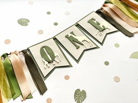 "Looking for Boy 1st Birthday decorations?! This eye-catching and stylish Safari ONE Banner is perfect to decorate the birthday baby's high chair or use as a photo prop, especially for Cake Smash pictures. --COLOR-- ⇒ Available in two colors themes: * Green, Gold, Ivory * Gray, Sand, Brown -- DETAILS-- * Made of high-quality design paper * Includes 3 pennants with green letters \"O N E\", gold animals: Giraffe, Elephant, Lion and embellished with cutest ribbon different texture trims * Each penn Jungle Theme Decorations, Cake Smash Pictures, Animals Giraffe, Green Letters, Wild Birthday Party, Boys First Birthday Party Ideas, Boys 1st Birthday Party Ideas, Birthday Highchair, Birthday Table Decorations