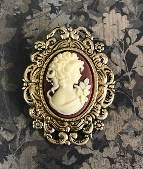 Cameo brooch. A dimensional cameo brooch with antiqued gold plated settings with a layed effect. The pretty resin cameo is rust brown and creme. The pinback has a bail so it can also be worn as a pendant. This piece measures 1 3/4 inches long. This would make a great cameo lover gift. A gift box is included. Antique Cameo Brooch, Jana Core, Cameo Tattoo, Mlp Redesigns, Trinkets Jewelry, Blue Anklet, Palm Beach Gardens Florida, Crystal Anklet, Sterling Silver Anklet