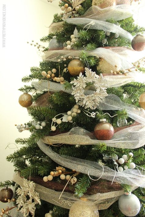 I am in love with this whimsical precious metals Christmas tree! Doesn't it just make you want to curl up with a blanket and watch lights dance for hours? Click through for how to's and more images! Christmas Tree With Tulle Garland, Christmas Tulle Decorations, Tulle Garland, Christmas Tree Ribbon Ideas, Tree Ribbon Ideas, Tulle Christmas Trees, Dream Christmas, Christmas Tree Ribbon, Ribbon Tree