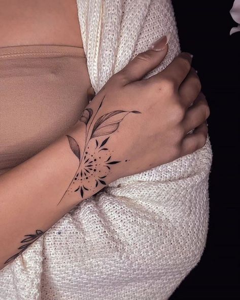 20 Wrist Tattoo Ideas for Women - Mom's Got the Stuff Arm Wrap Tattoos For Women Mandala, Top Of The Wrist Tattoos For Women, Half Cuff Tattoo, Hand Wrap Tattoos For Women, Thumb And Wrist Tattoo, Flower Wrap Around Wrist Tattoo, How To Connect Tattoos For A Sleeve, Dainty Hand Tattoos For Women Floral, Forearm And Wrist Tattoos