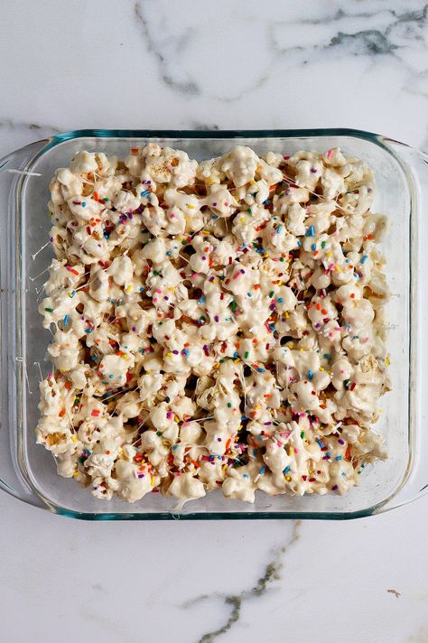 top down view of funfetti marshmallow popcorn treats in glass baking dish Cake Batter Popcorn Recipe, Marshmallow Puffcorn, Marshmallow Pretzel Treats, Marshmellow Popcorn Easy, White Chocolate Puffcorn, Popcorn Marshmallow Treats, Popcorn Fluff, Funfetti Popcorn Recipes, Easter Rice Crispy Treats